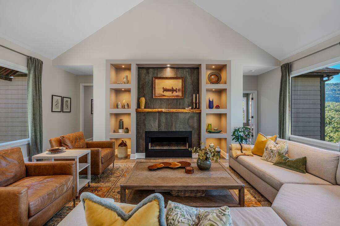 Great room fireplace in dark stone between lit niches